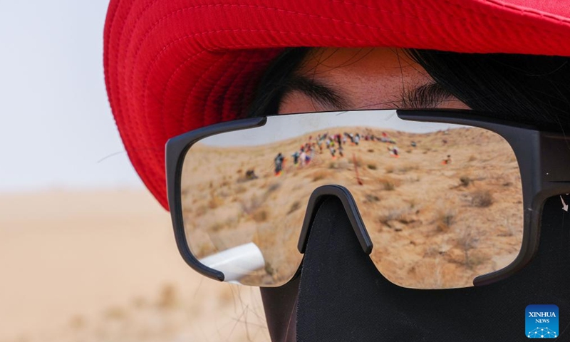 A scene of tree-planting is reflected on the goggles of a volunteer at the Zhonglin ecological public welfare forest base of Minqin County, northwest China's Gansu Province, April 21, 2026.

