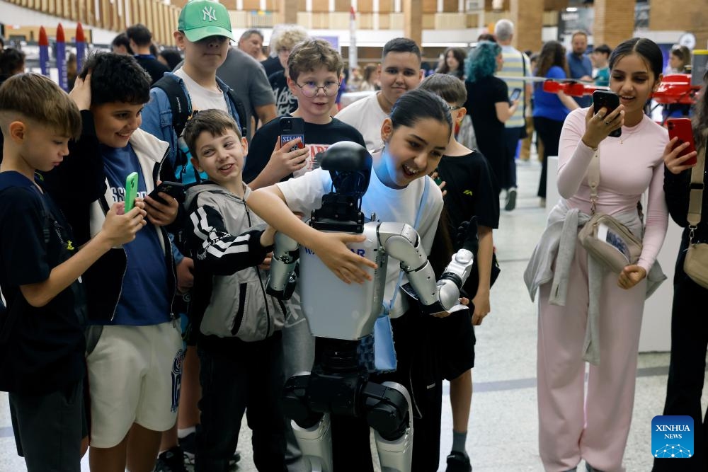 Visitors interact with a robot during the opening day of Spacefest 2026 at the Politehnica University in Bucharest, Romania, May 7, 2026. The Spacefest is an event dedicated to science, innovation and space exploration, with discussions and presentations about the future of space flight, emerging technologies and collaboration opportunities in the aerospace industry. (Photo by Cristian Cristel/Xinhua)

