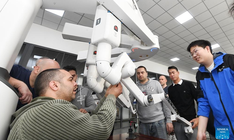A staff member (R) trains foreign clinical support engineers at the technical service training center of Harbin Sagebot Intelligent Medical Equipment Co., Ltd. in Harbin, northeast China's Heilongjiang Province, April 16, 2026. In recent years, the Harbin-based medical equipment enterprise has been dedicated to the development of high-end medical equipment as well as core technologies in surgical robots. Their robots have performed over 10,000 successful clinical surgeries worldwide, covering key departments including general surgery, urology, gynaecology, and thoracic surgery. (Photo by Liu Yang/Xinhua)

