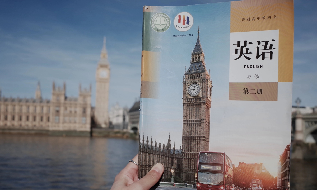 Zephyrine, a Chinese student studying in the UK, holding an English textbook used in China, captures a photo that brings the textbook illustration of Big Ben and the real Big Ben into the same frame on April 7, 2026. Photo: Courtesy of Zephyrine