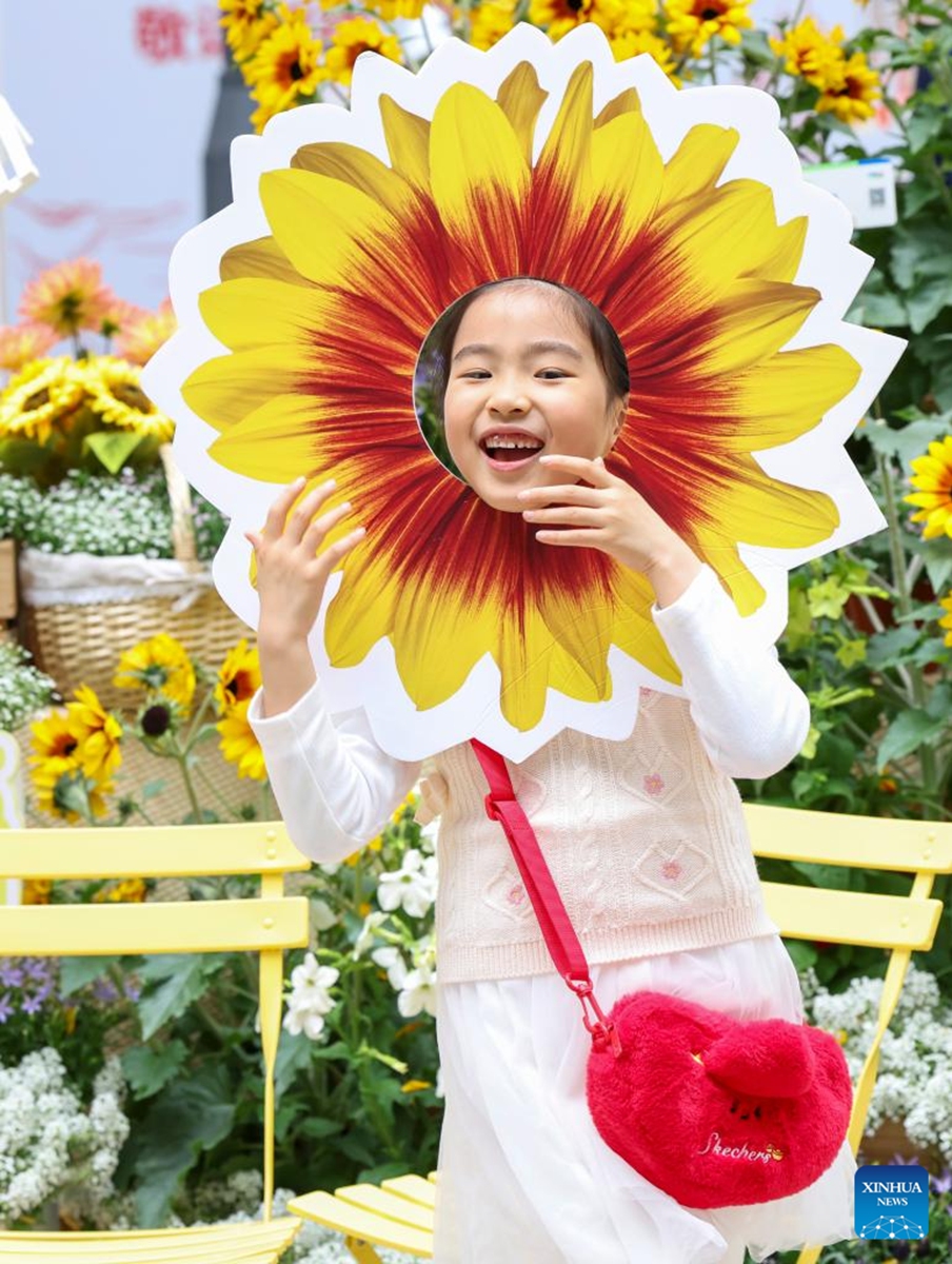 A girl poses for photos at a flower fair in Huangpu District of Shanghai, east China, April 18, 2026. The 2026 Shanghai International Flower Show opened on Saturday with events in two main venues, 10 sub-venues and multiple exhibition spots across the city. (Xinhua/Chen Haoming)