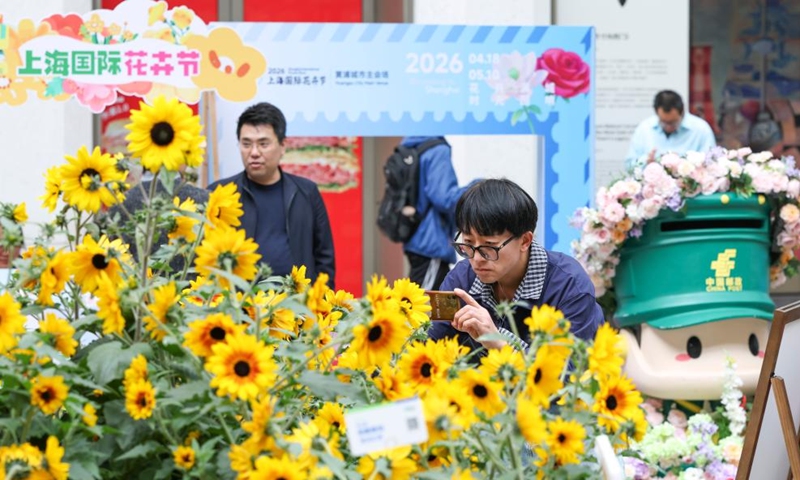 A tourist takes photos of flowers at a flower fair in Huangpu District of Shanghai, east China, April 18, 2026. The 2026 Shanghai International Flower Show opened on Saturday with events in two main venues, 10 sub-venues and multiple exhibition spots across the city. (Xinhua/Chen Haoming)