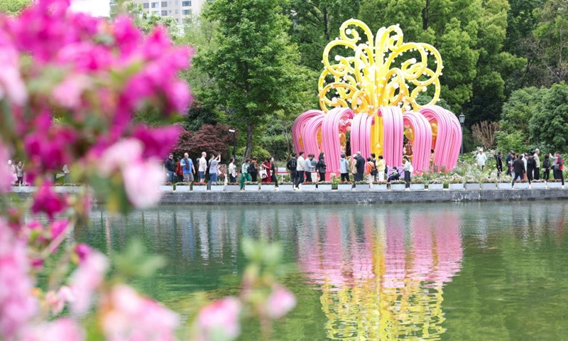 Tourists view flowers by a lake in Huangpu District of Shanghai, east China, April 18, 2026. The 2026 Shanghai International Flower Show opened on Saturday with events in two main venues, 10 sub-venues and multiple exhibition spots across the city. (Xinhua/Chen Haoming)