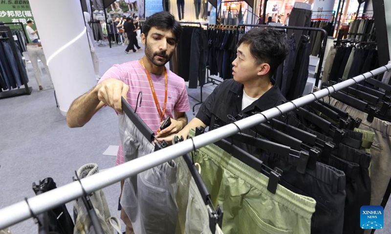 A foreign merchant talks with an exhibitor during the 28th Straits Textile and Clothing Fair in Shishi, southeast China's Fujian Province, April 18, 2026. The fair kicked off here on Saturday. (Xinhua/Jiang Kehong)