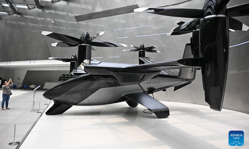 A visitor takes photos of a flying vehicle displayed at Xpeng Technology Park in Tianhe District of Guangzhou, south China's Guangdong Province on March 24, 2026.

