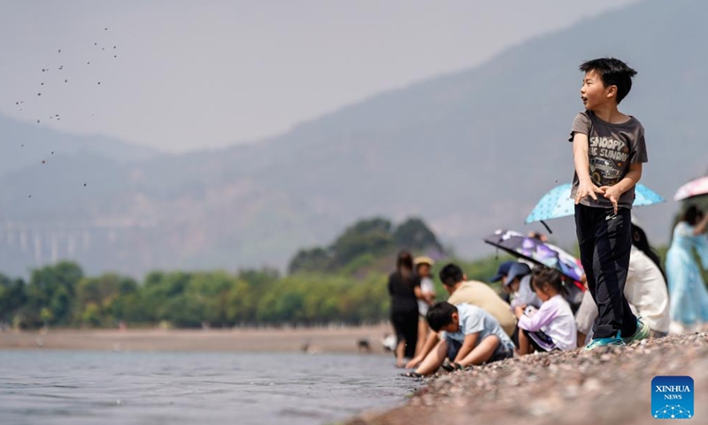 Children play by the Fuxian Lake in Yuxi City, southwest China's Yunnan Province, April 18, 2026. Fuxian Lake stretches out like a sapphire cradled by hills. It boasts Class I water quality, while its shores are now lined with bike paths and dotted with kayaks. (Xinhua/Peng Yikai)

