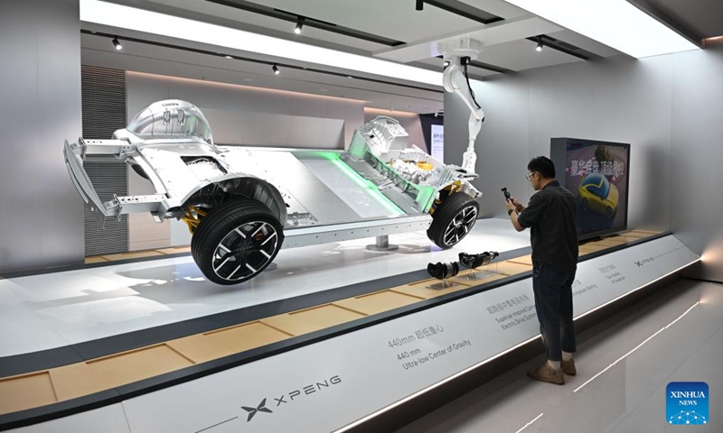 A visitor takes photos of a new energy vehicle chassis displayed at Xpeng Technology Park in Tianhe District of Guangzhou, south China's Guangdong Province on March 24, 2026.

