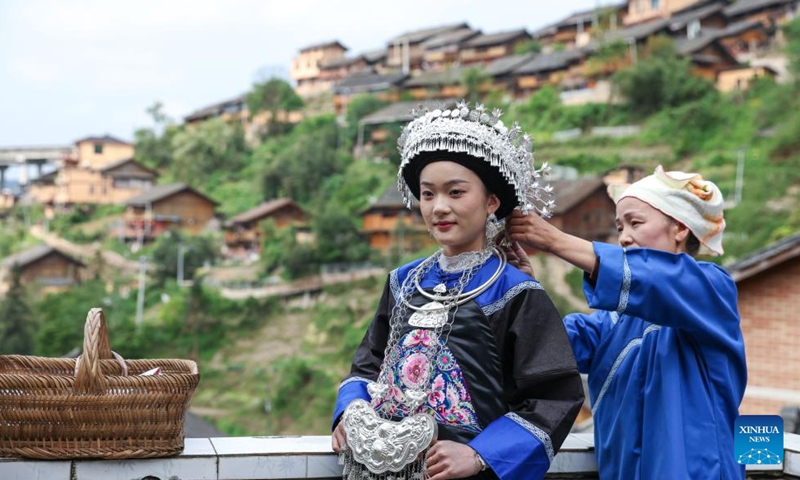 A woman of the Dong ethnic group is helped with her traditional costumes for an event celebrating the Sanyuesan Festival at Zhenyuan County in southwest China's Guizhou Province, April 19, 2026. The Sanyuesan Festival is a traditional festival celebrated on the third day of the third lunar month by various ethnic groups in China. The festival falls on April 19 this year. (Xinhua/Yang Wenbin)

