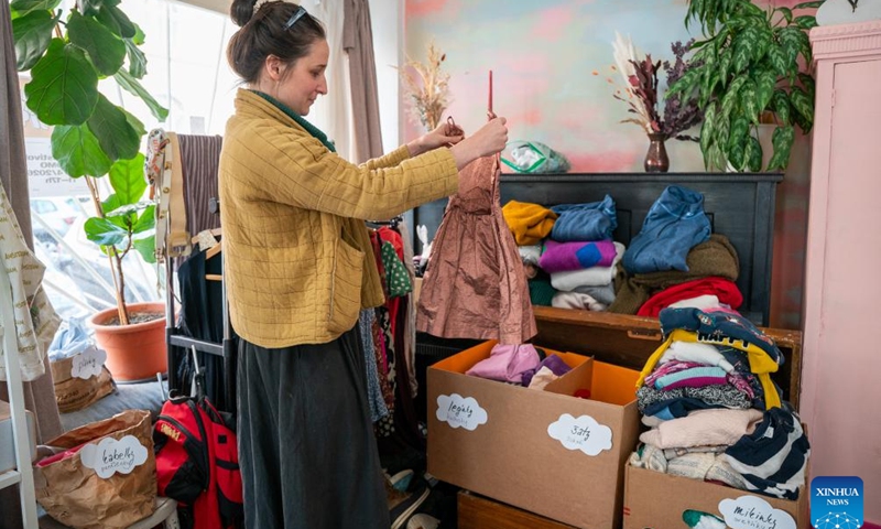 A woman chooses clothes at the Swap Festival in Prague, the Czech Republic, April 21, 2026. This year's Swap Festival takes place from April 20 to 26 across multiple locations in Prague, encouraging people to bring items they no longer need such as clothes and books to exchange, promoting repair, reuse, and sharing. (Photo by Dana Kesnerova/Xinhua)

