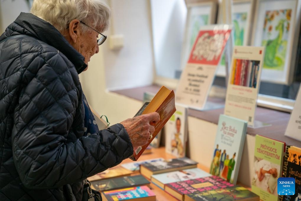 A woman reads a book at the Swap Festival in Prague, the Czech Republic, April 21, 2026. This year's Swap Festival takes place from April 20 to 26 across multiple locations in Prague, encouraging people to bring items they no longer need such as clothes and books to exchange, promoting repair, reuse, and sharing. (Photo by Dana Kesnerova/Xinhua)

