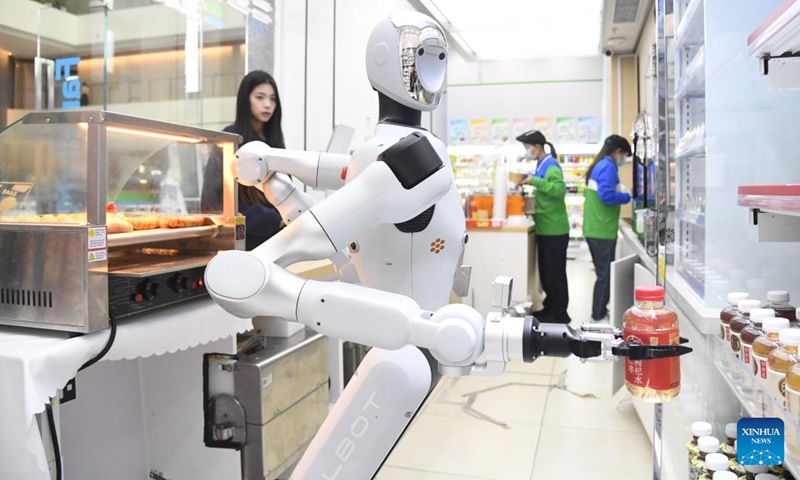 A humanoid robot grabs a bottle of beverage at a convenience store in Haidian District of Beijing, capital of China, April 22, 2026. An embodied large model robot has recently been deployed in a convenience store in Haidian District to provide regular service. The robot is responsible for greeting customers, answering product inquiries, providing promotion information, and delivering goods. (Xinhua/Ren Chao)

