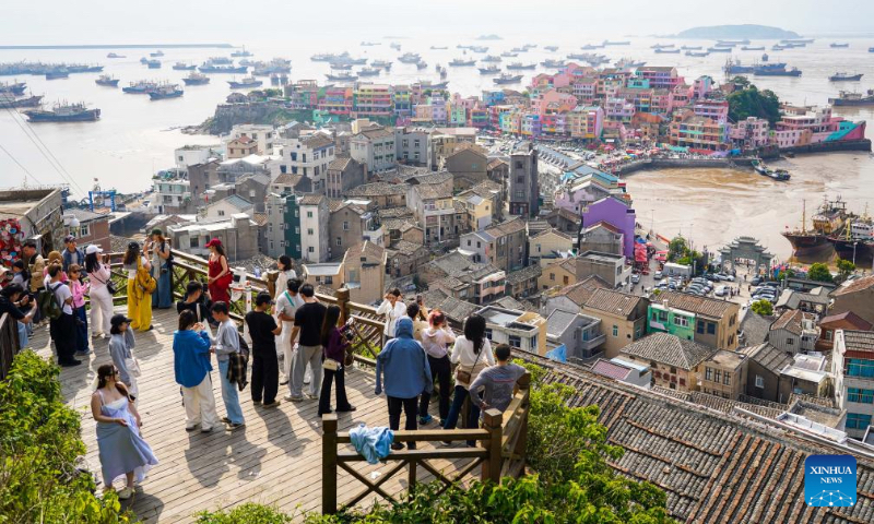 People look out on Qilin Mountain in Shitang Town, Wenling City, east China's Zhejiang Province, May 2, 2026. Shitang Town, located in Wenling City of Zhejiang Province, is a traditional fishing port surrounded by the sea on three sides. During this year's May Day holiday, the town hosted a variety of fishing culture activities, drawing tourists from across the country. (Xinhua/Jiang Han)
