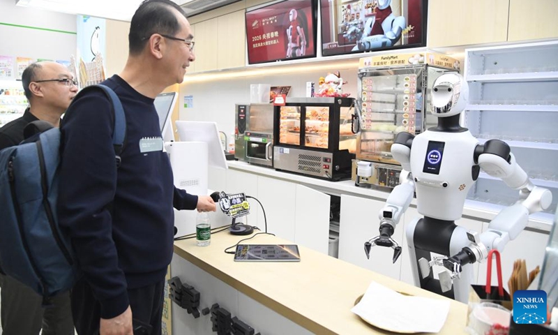 Customers purchase goods by interacting with a humanoid robot at a convenience store in Haidian District of Beijing, capital of China, April 22, 2026. An embodied large model robot has recently been deployed in a convenience store in Haidian District to provide regular service. The robot is responsible for greeting customers, answering product inquiries, providing promotion information, and delivering goods. (Xinhua/Ren Chao)

