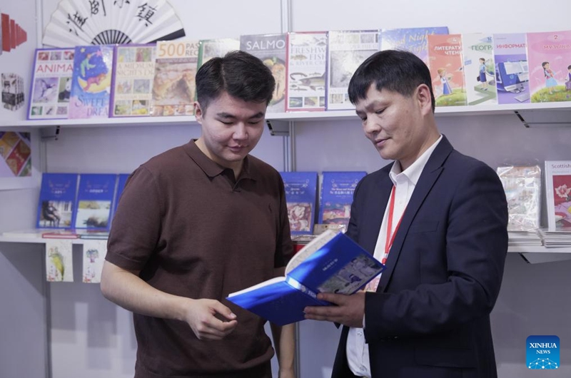 An exhibitor from China introduces a book to a visitor during the Eurasian Book Fair in Astana, Kazakhstan, April 22, 2026. This event is held here from April 22 to 26. (Photo by Kalizhan Ospanov/Xinhua)