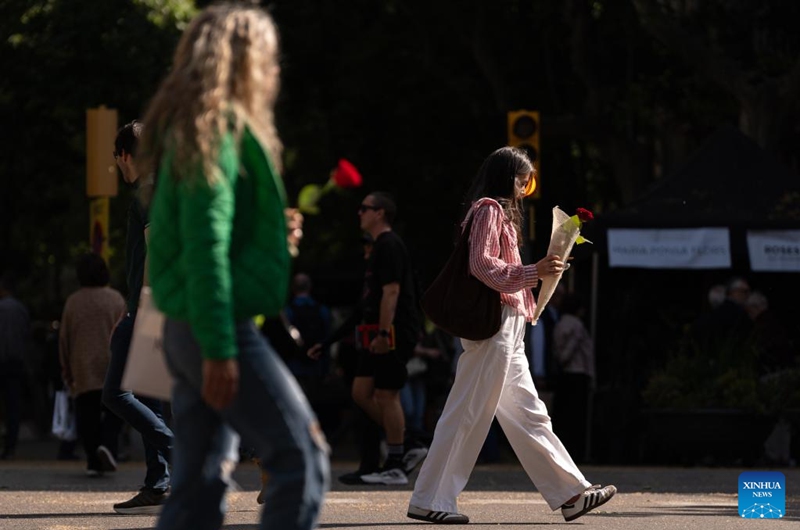 Women holding roses are seen in Barcelona, Spain, April 23, 2026. Large crowds filled the Spanish city of Barcelona on Thursday as people took to the streets to celebrate Sant Jordi, a traditional festival combining romance and reading. (Photo by Joan Gosa/Xinhua)