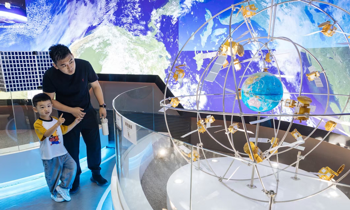A man and a child observe a model of satellite constellations on display, featuring orbiting spacecraft encircling a miniature Earth, at the China Space Museum in Beijing, China, on April 24, as the day marks the 11th China Space Day, which this year coincides with the 70th anniversary of China's space program. Photo: Li Hao/GT