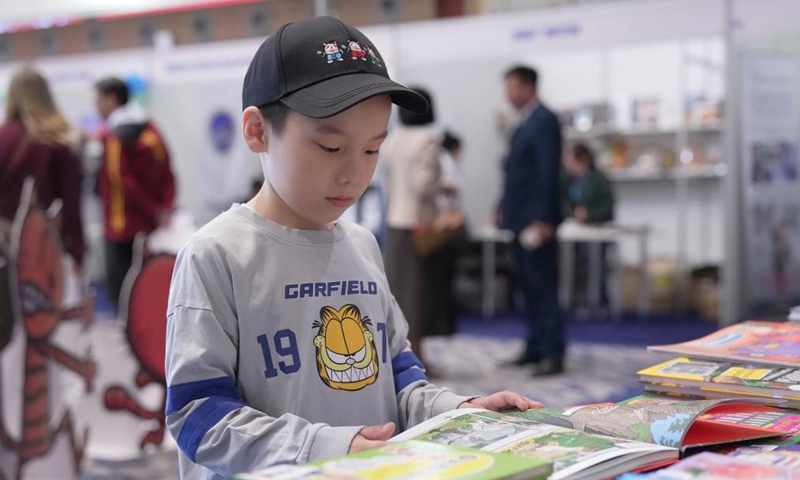 A boy browses a book during the Eurasian Book Fair in Astana, Kazakhstan, April 22, 2026. This event is held here from April 22 to 26. (Photo by Kalizhan Ospanov/Xinhua)