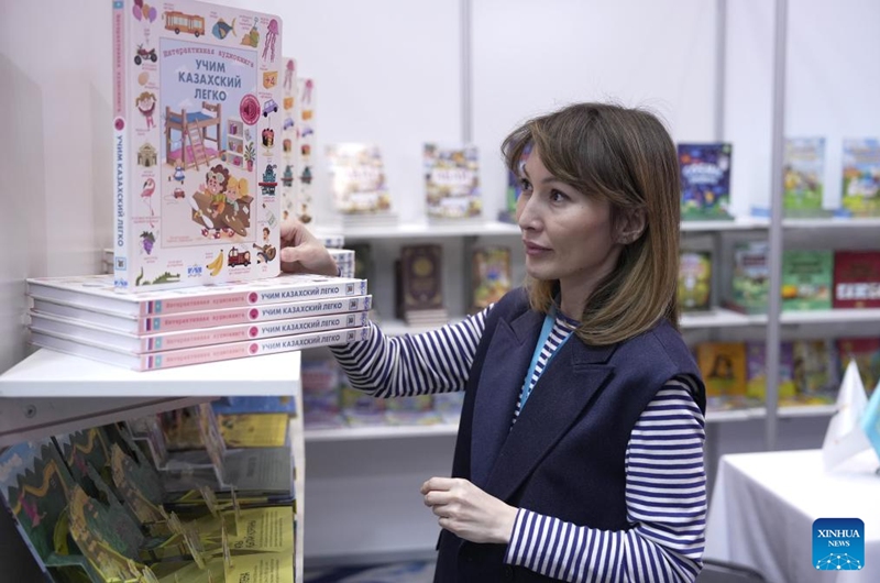 An exhibitor arranges books during the Eurasian Book Fair in Astana, Kazakhstan, April 22, 2026. This event is held here from April 22 to 26. (Photo by Kalizhan Ospanov/Xinhua)