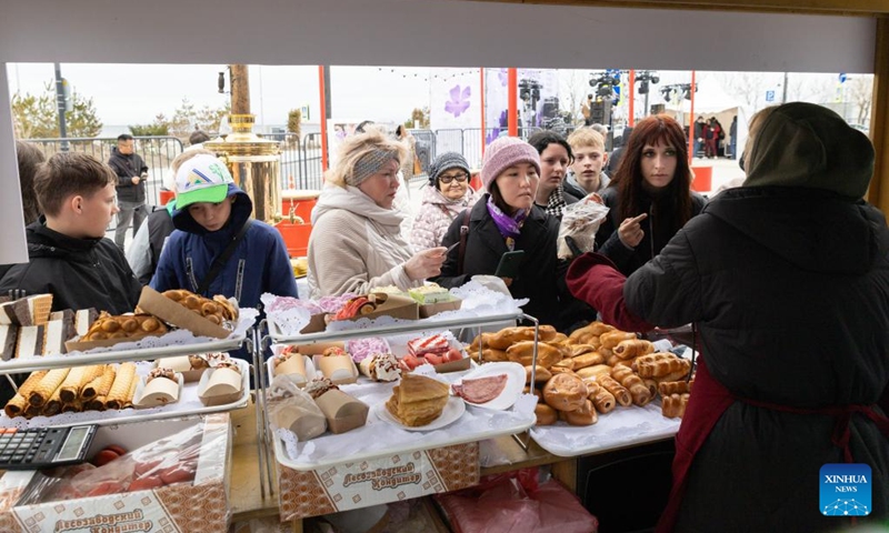 Visitors buy food during the rhododendron festival in Vladivostok, Russia, April 25, 2026. The rhododendron festival was held here on Saturday to promote rhododendron-themed tourism and enhance its appeal to tourists. (Photo by Andrey Matveenko/Xinhua)