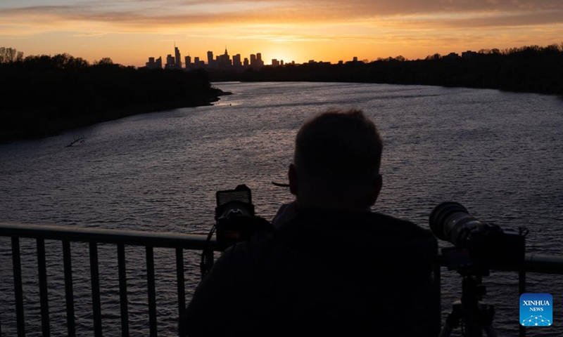 A man takes photos of the sunset scenery from a bridge over the Vistula River in Warsaw, Poland, April 23, 2026. (Photo by Jaap Arriens/Xinhua)