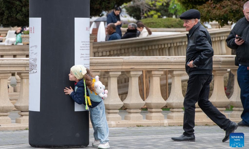 A girl hides behind a giant wine bottle installation as she plays hide-and-seek with adults during the Jazz and Wine Festival at a seaside park in Baku, Azerbaijan, April 25, 2026. The ten-day event integrates Azerbaijan's indigenous wine-making traditions with musical art, bringing a relaxing and vibrant vibe to the city and drawing numerous locals and tourists for leisure and wine tasting. (Xinhua/Chen Junfeng)