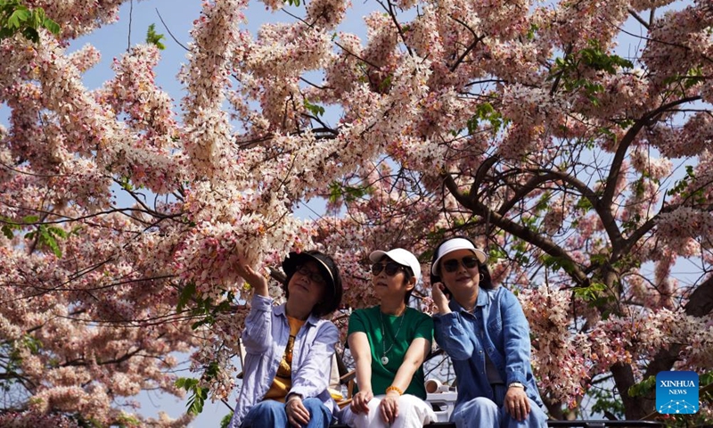 Tourists pose for photos with flowers in Shiping County, southwest China's Yunnan Province, April 23, 2026. (Photo by Liang Zhiqiang/Xinhua)
