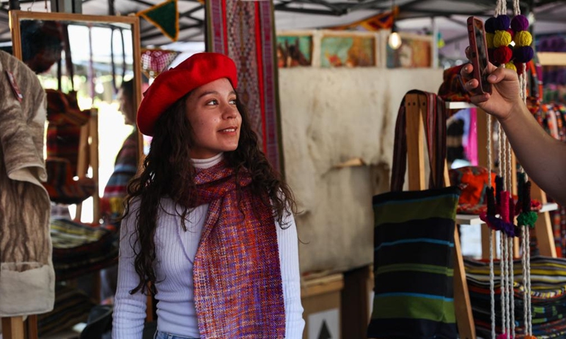 A woman tries a woolen hat at a wool festival in Santiago, Chile, April 25, 2026. (Xinhua/Zhou Jiayi)
