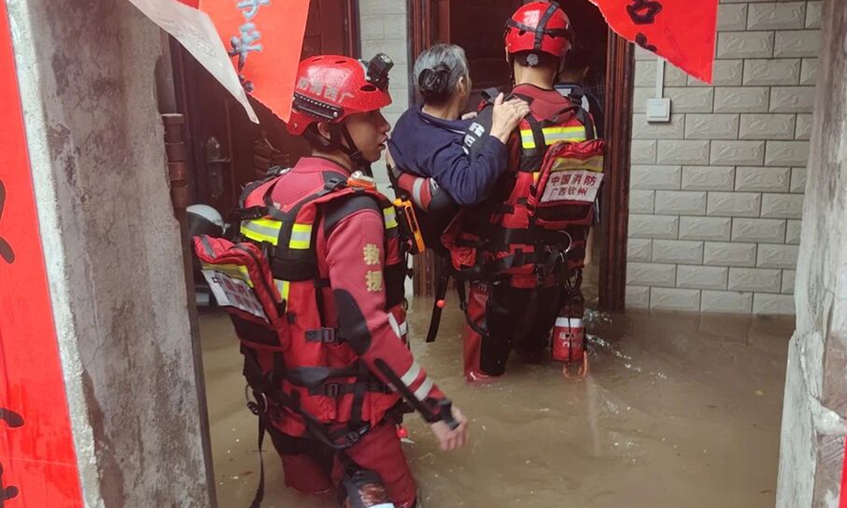 Qinzhou Fire and Rescue personnel carry an elderly resident through fast flowing floodwaters in Chengxi community on Monday, one of the hardest hit areas where water surged over roads, reached knee level in some sections, inundated street side shops and left residents trapped at home or along the way. Photo: Qinzhou Fire Department's official WeChat account.