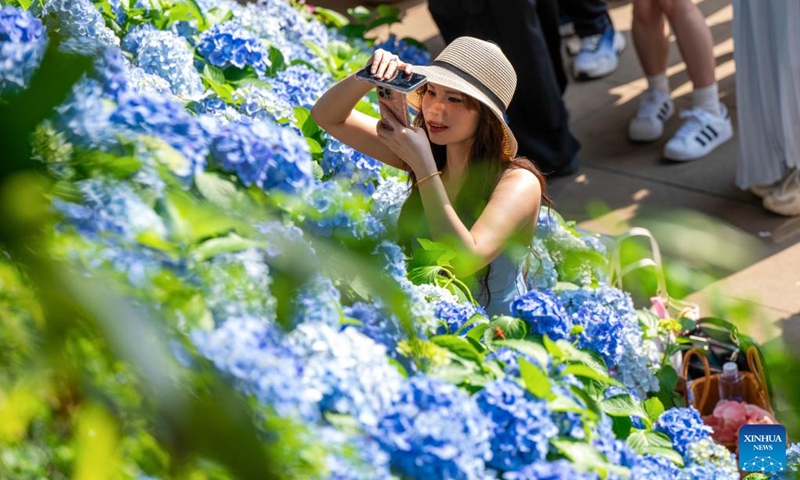A tourist takes photos of flowers at the Qingxiu Mountain scenic area in Nanning, south China's Guangxi Zhuang Autonomous Region, April 25, 2026. (Photo by He Huawen/Xinhua)