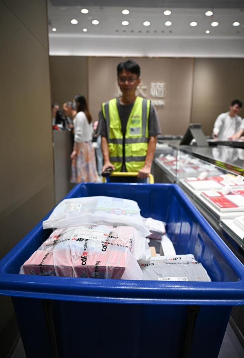 A staff member carries duty-free items for customers at a duty-free shop in Haikou, south China's Hainan Province, April 25, 2026. (Xinhua/Pu Xiaoxu)