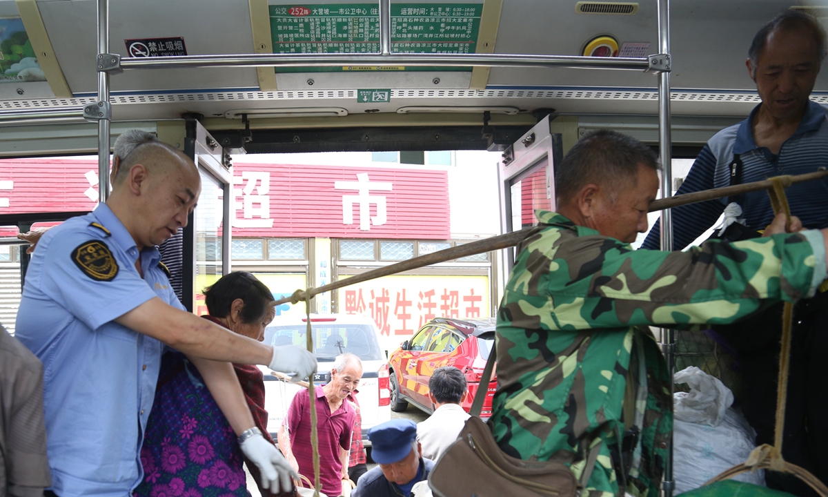 The driver helps farmers with their bags as they get off the Route 252 bus. Photo: Courtesy of Yang Guangwei