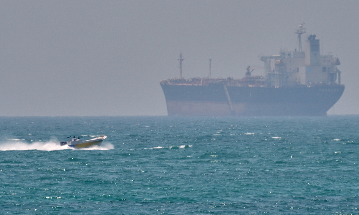 A boat sails past a tanker anchored on the Strait of Hormuz off the coast of Iran's Qeshm Island on April 18, 2026. Photo: VCG