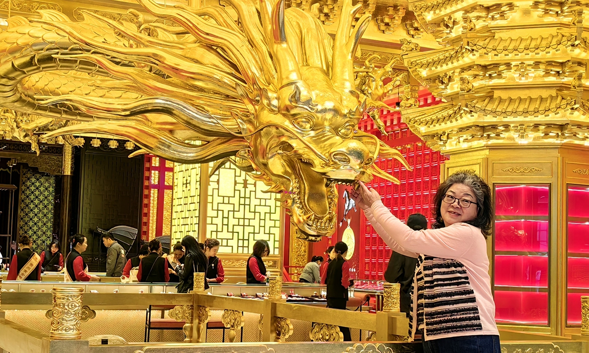 A customer strokes a golden dragon for a photo at a gold shop in Guiyang, Southwest China's Guizhou Province, on April 29, 2026. The shop began its trial operation on the same day, offering services including gold bar sales, on-site gold processing, finished gold product sales, and gold recycling. Photo: VCG