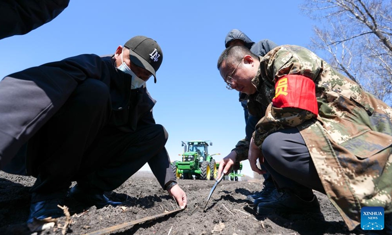 Agricultural technicians check a newly-seeded field at Youyi Farm Co., Ltd. under Beidahuang Group in northeast China's Heilongjiang Province, April 28, 2026.

