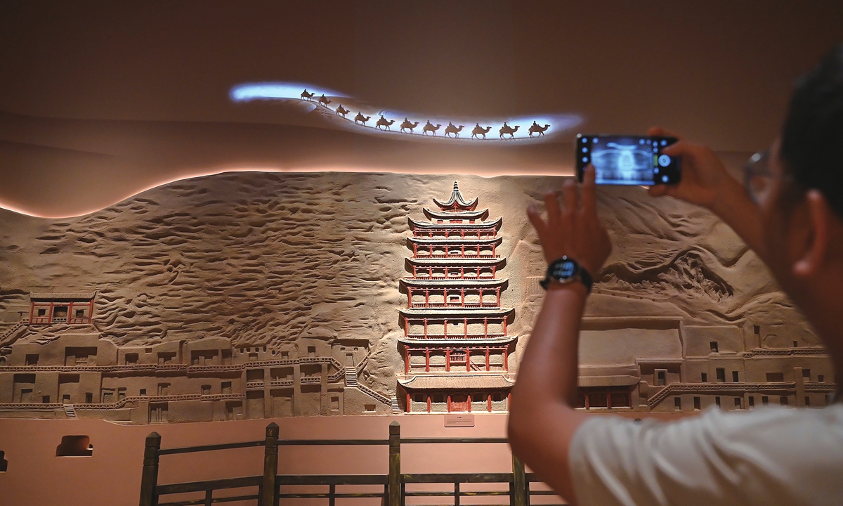A man takes a photo at the Dunhuang grottoes art exhibition on Wednesday, which is scheduled from May 1 to October 31 at the Guangzhou Museum of Art in South China's Guangdong Province. The exhibition will feature seven 1:1 high-precision replica caves and more than 150 newly created works. Photo: VCG