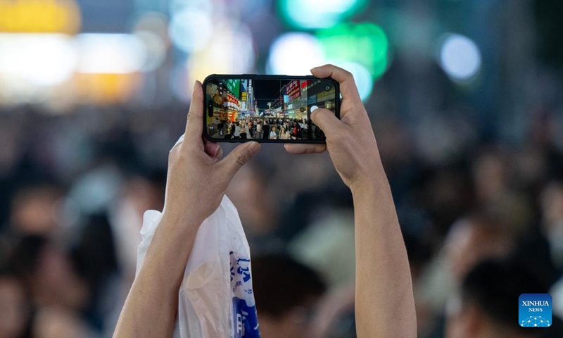 A tourist takes photos at a pedestrian street in Changsha, central China's Hunan Province, April 25, 2026.

Changsha at night features diverse modes of business: live-streaming, band performance, period costume photography and night-market food, all contributing to the nighttime economic vitality of the city. (Xinhua/Liu Jie)