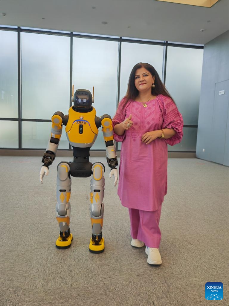 Rashida Shoukat Sial poses for a photo with the humanoid robot Guangzi at the Hubei Humanoid Robot Innovation Center in Wuhan, central China's Hubei Province, April 25, 2026. (Xinhua/Yue Wenwan)

