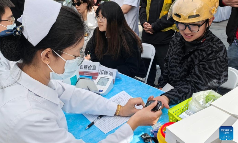 A volunteer tests blood sugar level for a deliveryman in Chaoyang District, Beijing, capital of China, April 28, 2026. A volunteer activity was held here on Tuesday to offer free medicine consultations, haircuts and knowledge contests for young people in new employment sectors. (Xinhua/Li Xin)

