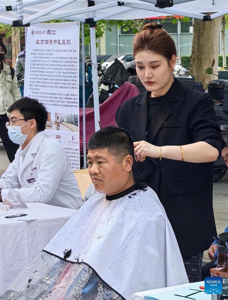 A volunteer offers free haircuts to a deliveryman in Chaoyang District, Beijing, capital of China, April 28, 2026. A volunteer activity was held here on Tuesday to offer free medicine consultations, haircuts and knowledge contests for young people in new employment sectors. (Xinhua/Li Xin)

