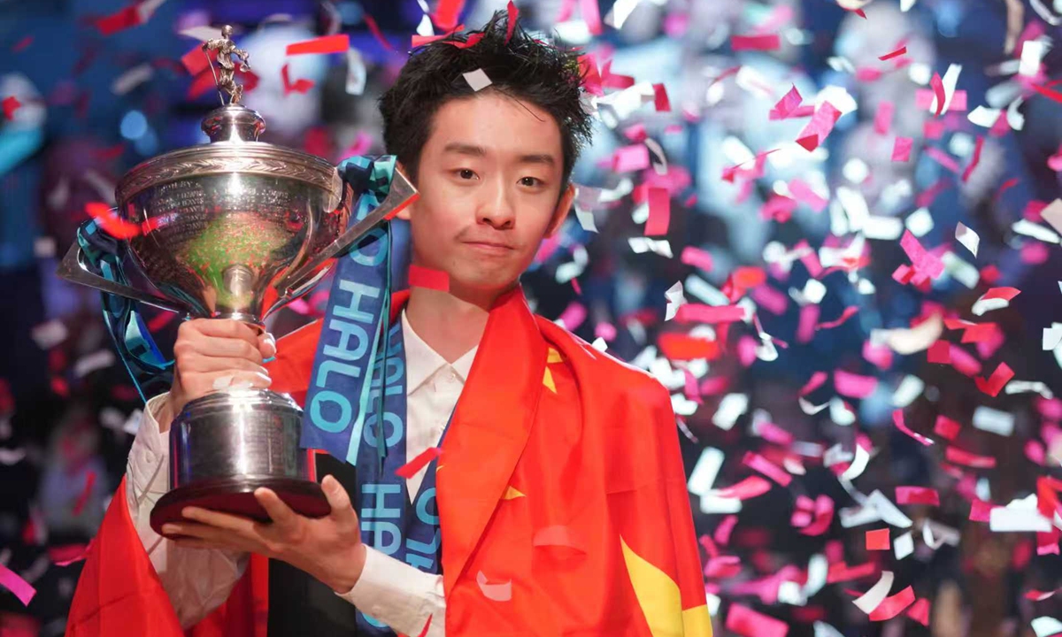 Chinese snooker player Wu Yize poses with the trophy wearing the Chinese national flag, after winning the World Snooker Championship defeating England's Shaun Murphy in Sheffield, England, on May 4, 2026. Photo: VCG