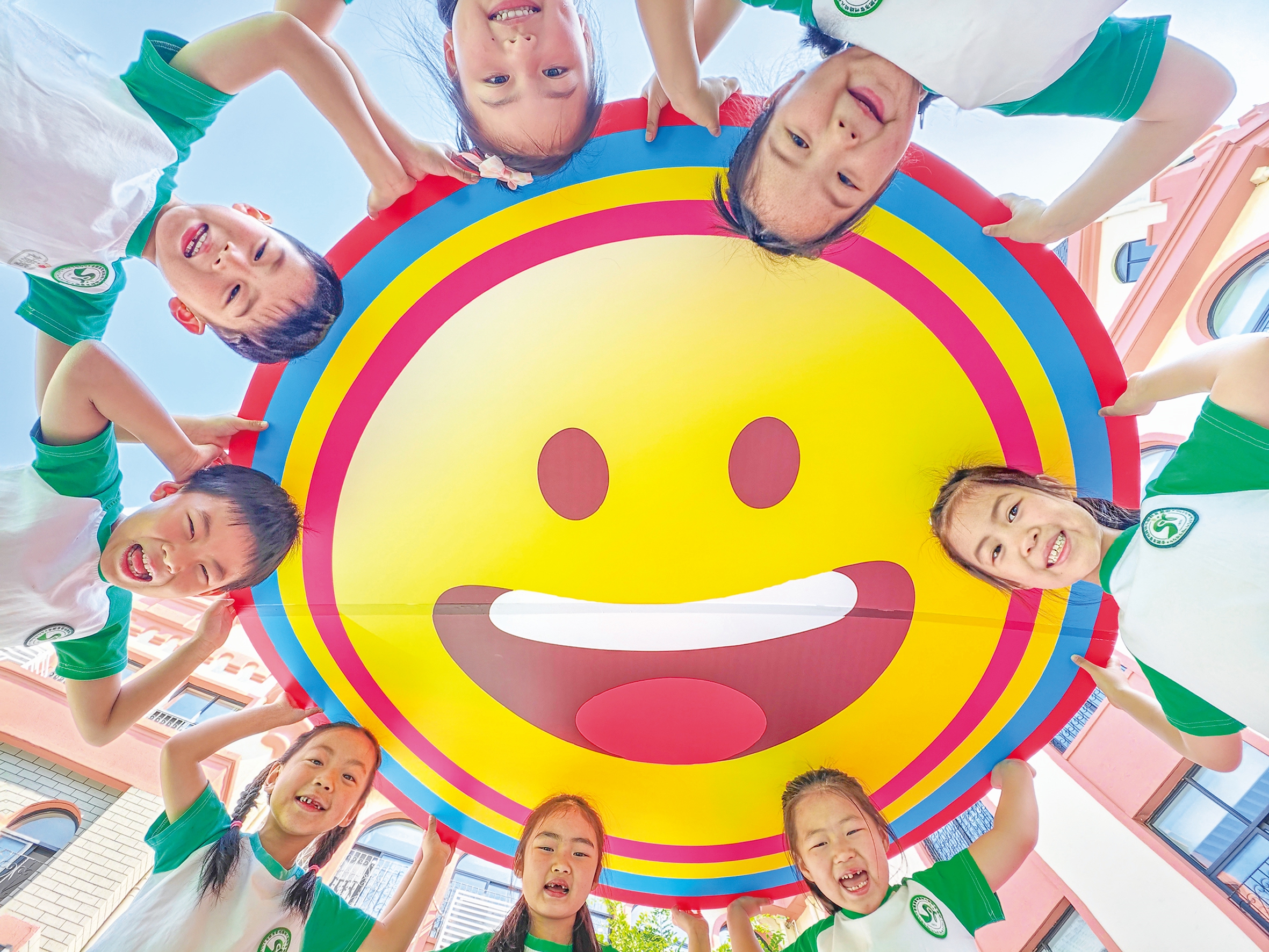 Children at a kindergarten in Hefei, Anhui Province, East China, hold smile cards, learn etiquette, exchange greetings, and play with rainbow bubbles during a themed activity 