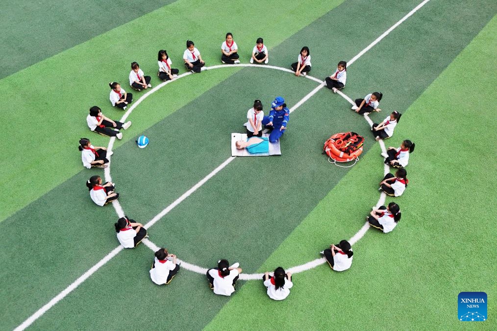 An aerial drone photo taken on May 11, 2026 shows a member of the Blue Sky Rescue Team demonstrating cardiopulmonary resuscitation (CPR) at a primary school in Tangshan, north China's Hebei Province. A variety of activities were held across the country marking the upcoming National Disaster Prevention and Reduction Day. (Photo by Zhu Dayong/Xinhua)