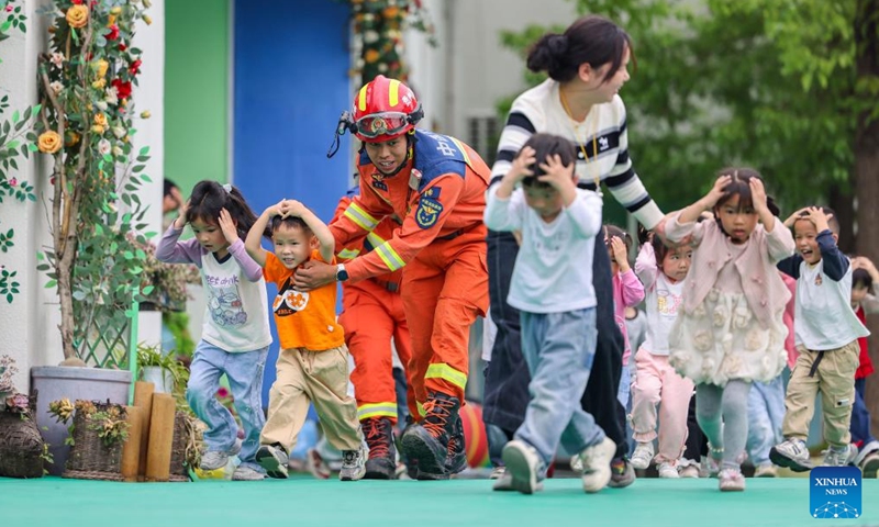 Children take part in an earthquake emergency evacuation drill under the guidance of a firefighter at a kindergarten in Yuping Dong Autonomous County of Tongren City, southwest China's Guizhou Province, May 11, 2026. A variety of activities were held across the country marking the upcoming National Disaster Prevention and Reduction Day. (Photo by Hu Panxue/Xinhua)