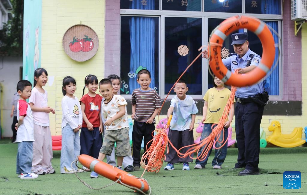 A police officer teaches children water safety knowledge at a kindergarten in Leshan, southwest China's Sichuan Province, May 11, 2026. A variety of activities were held across the country marking the upcoming National Disaster Prevention and Reduction Day. (Photo by Li Huashi/Xinhua)