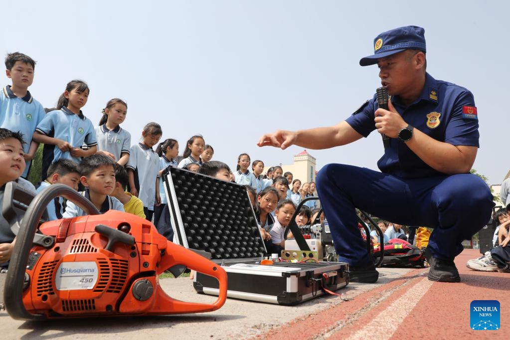 A firefighter introduces firefighting and rescue equipment to students at a primary school in Wenxian County of Jiaozuo City, central China's Henan Province, May 11, 2026. A variety of activities were held across the country marking the upcoming National Disaster Prevention and Reduction Day. (Photo by Xu Hongxing/Xinhua)