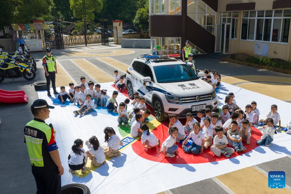 A drone photo taken on May 11, 2026 shows police officers teaching children knowledge about vehicle blind spots at a kindergarten in Wuhu, east China's Anhui Province. A variety of activities were held across the country marking the upcoming National Disaster Prevention and Reduction Day. (Photo by Xiao Benxiang/Xinhua)