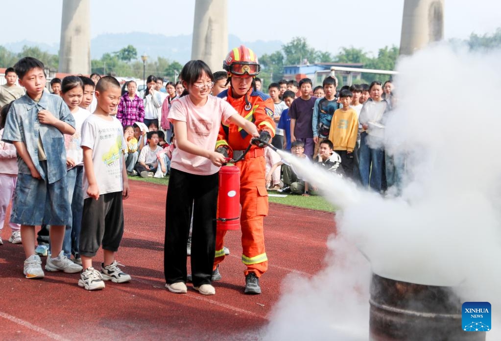 A firefighter teaches students to use fire extinguishers at a primary school in Huaying, southwest China's Sichuan Province, May 11, 2026. A variety of activities were held across the country marking the upcoming National Disaster Prevention and Reduction Day. (Photo by Qiu Haiying/Xinhua)