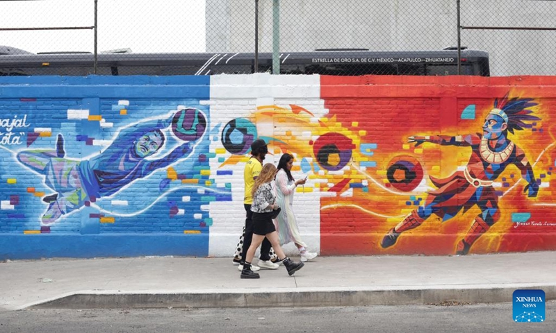 People walk past football-themed graffiti in Mexico City, capital of Mexico, May 10, 2026. Mexico is set to cohost the 2026 FIFA World Cup in June and July of this year, along with the United States and Canada, becoming the first country in the world to host three World Cup tournaments. (Photo: Xinhua)