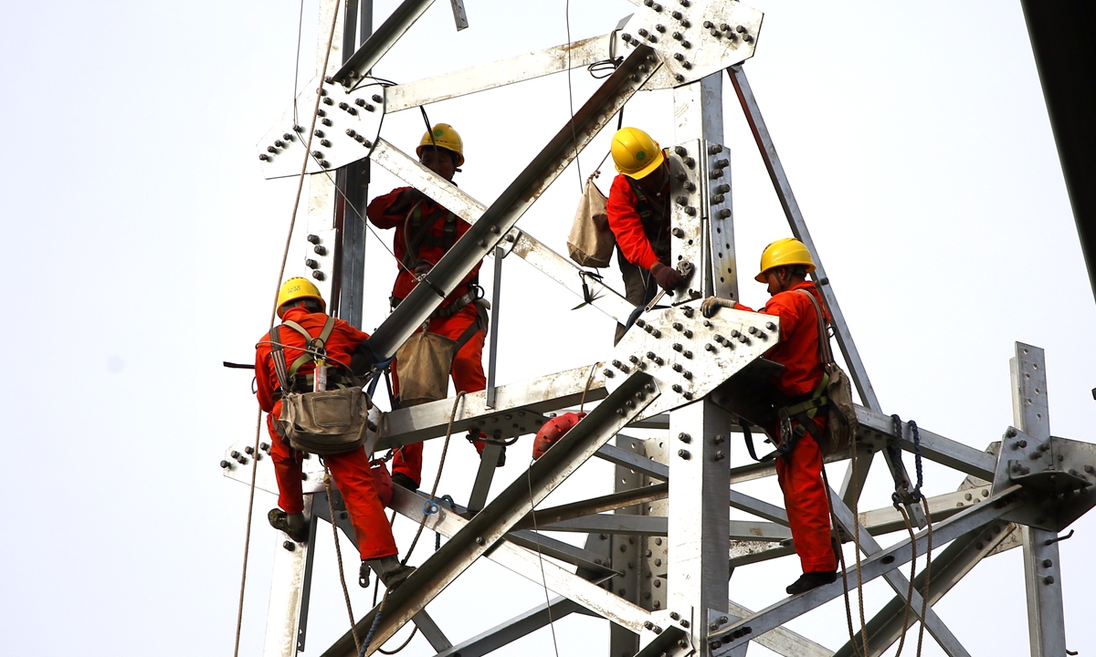 Construction employees work on a transmission tower as part of a power transmission expansion project in Yuhuan, East China's Zhejiang Province, on May 11, 2026. The city is fully committed to accelerating the development of its power networks, and enhancing power supply capacity across the region to support local development. Photo: VCG