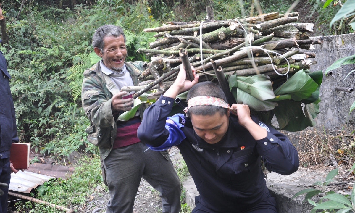 Police officer Gao Yanping helps an elderly villager carry firewood on his back in Dulongjiang, Yunnan Province. Photo: Courtesy of Dulongjiang Frontier Police Station